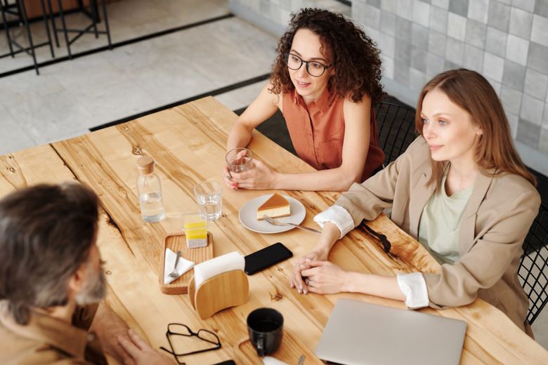 Three colleagues in a relaxed meeting over coffee outdoors — photo by Edmond Dantès on Pexels