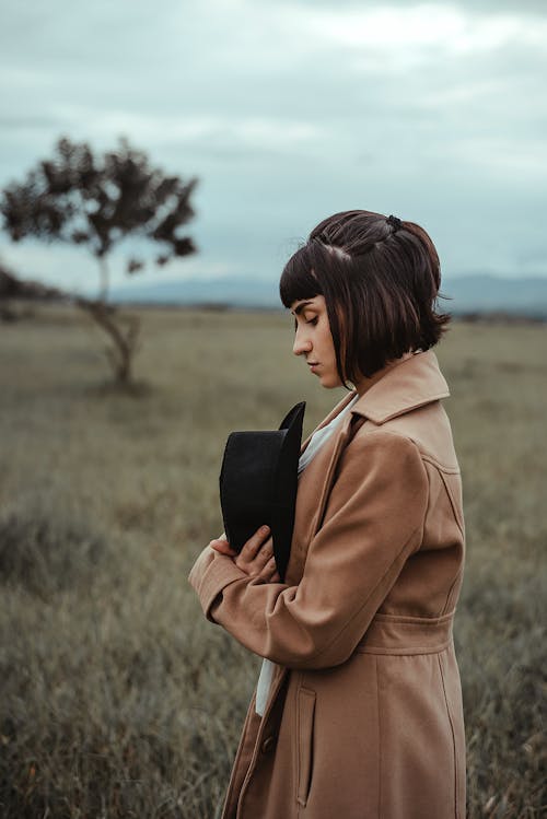 A Woman in Brown Coat Standing in a Field