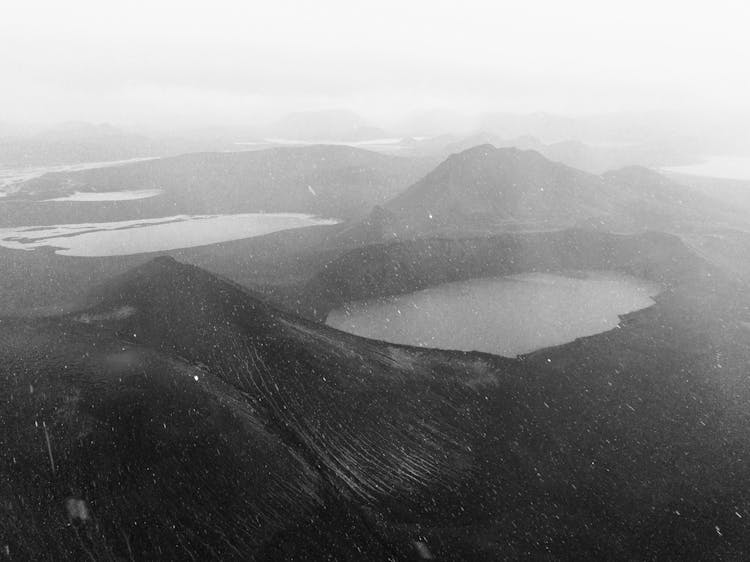 Volcanic Terrain With Mountains And Geothermal Lake In Fog