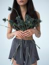 一位年轻女子手持一束精致的海冬青花，散发着优雅与自然之美