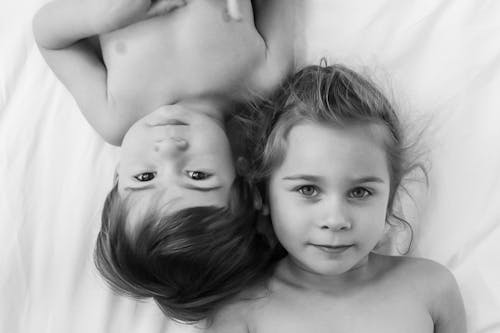 Free Shirtless Girl and Boy Lying on Bed Stock Photo