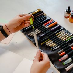Hands taking a pen from a roll case full of brush pens