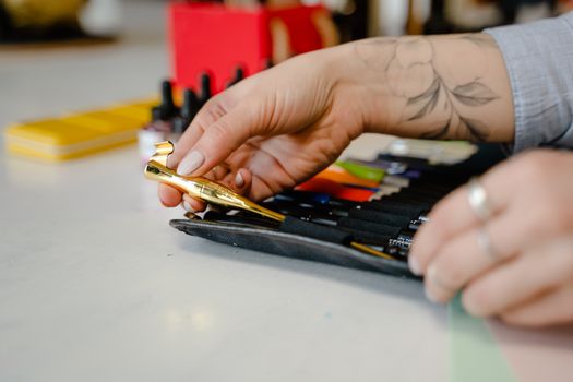 A close-up of an artist organizing calligraphy pens on a table indoors.