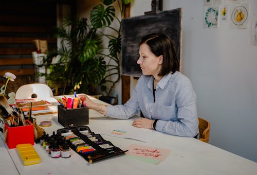 Woman in Blue Dress Shirt Sitting by the Table