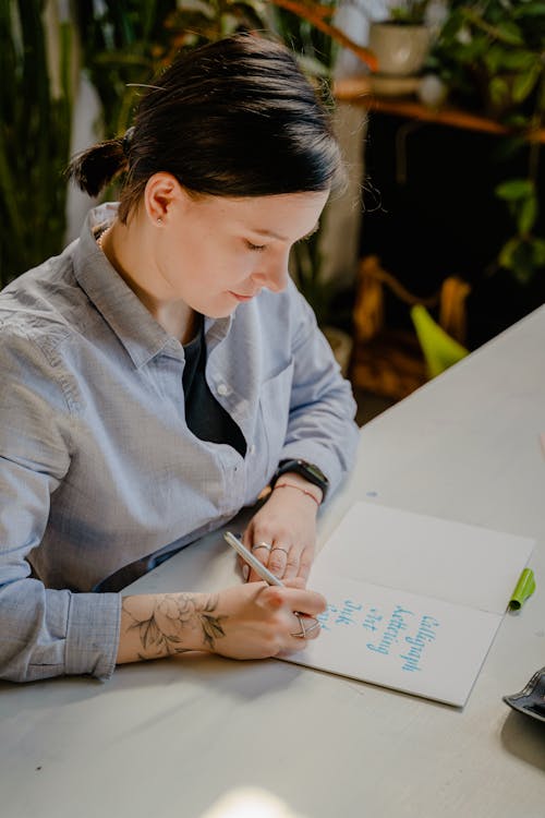 Woman in Gray Dress Shirt Writing on White Paper