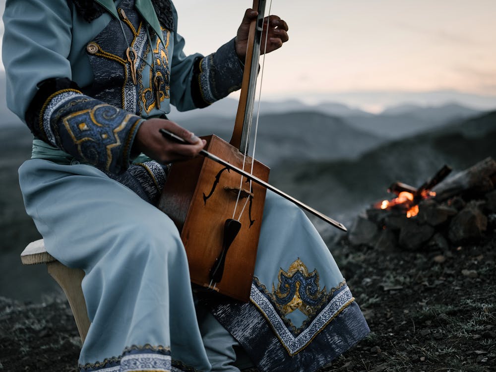 Crop person playing traditional Mongolian stringed instrument in countryside
