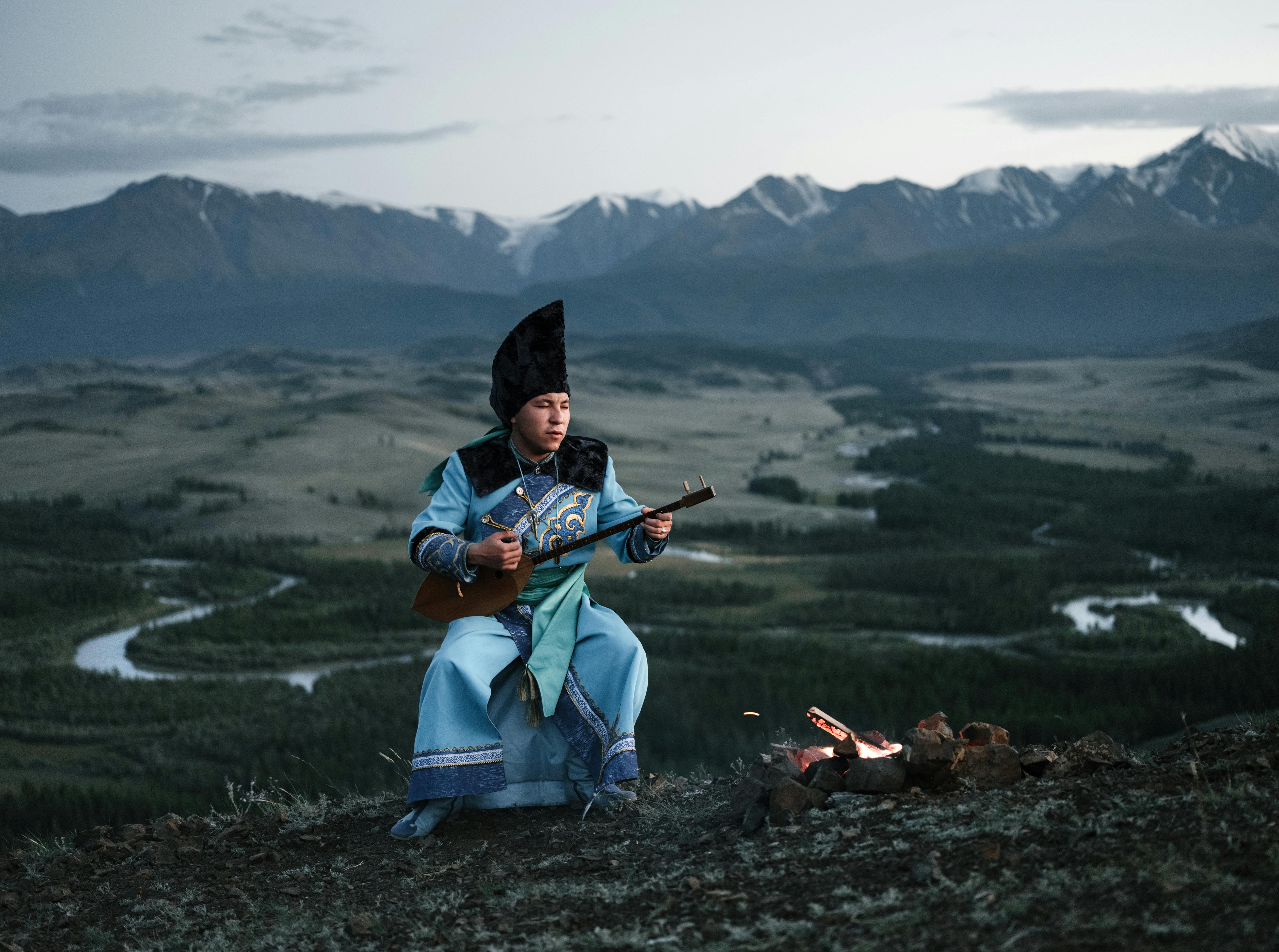 Crop person standing near bonfire with Mongolian folk instrument in ...