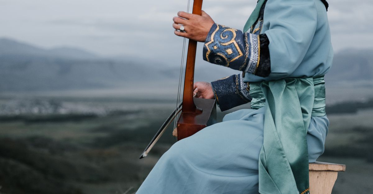 Stringed Instruments Ethnic Young ethnic man in national costume playing traditional bowed stringed ...