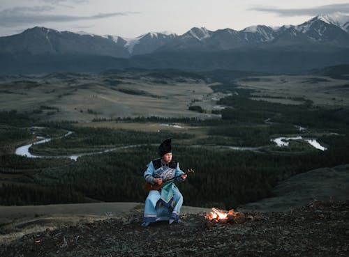 Young Mongolian male musician playing dombor in valley