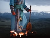 Crop person standing near bonfire with Mongolian folk instrument in valley