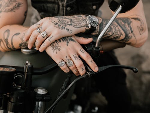 Photo of Person's Hands With Tattoos and Rings
