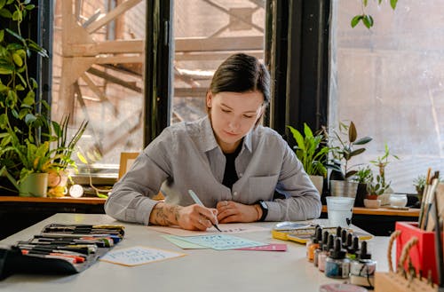 Woman in Gray Long Sleeve Shirt Sitting at Table