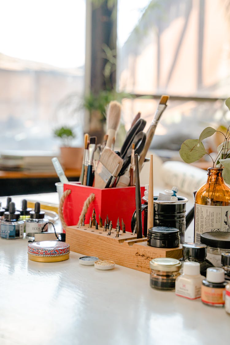 Set Of Paint Brushes And Ink Bottles On Table