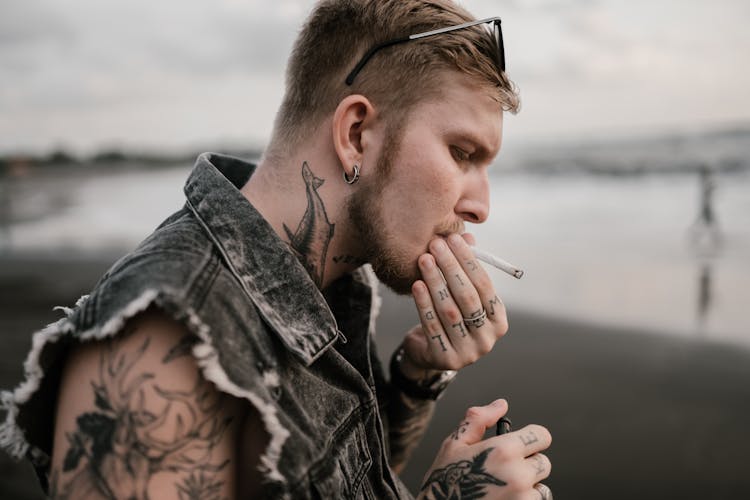 Crop Brutal Guy Smoking Cigarette On Sea Beach In Evening