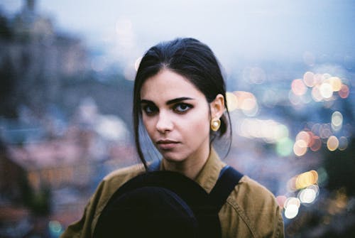 Young brunette in earrings standing in bokeh background
