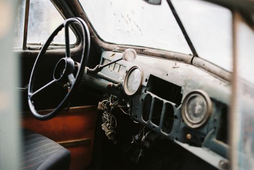 Free Interior of old fashioned automobile with seat and dirty windshield near big steering wheel and wire bundle above in daylight Stock Photo