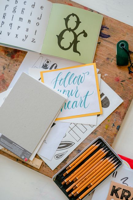 Creative workspace with calligraphy tools, lettering projects, and pencils on a desk