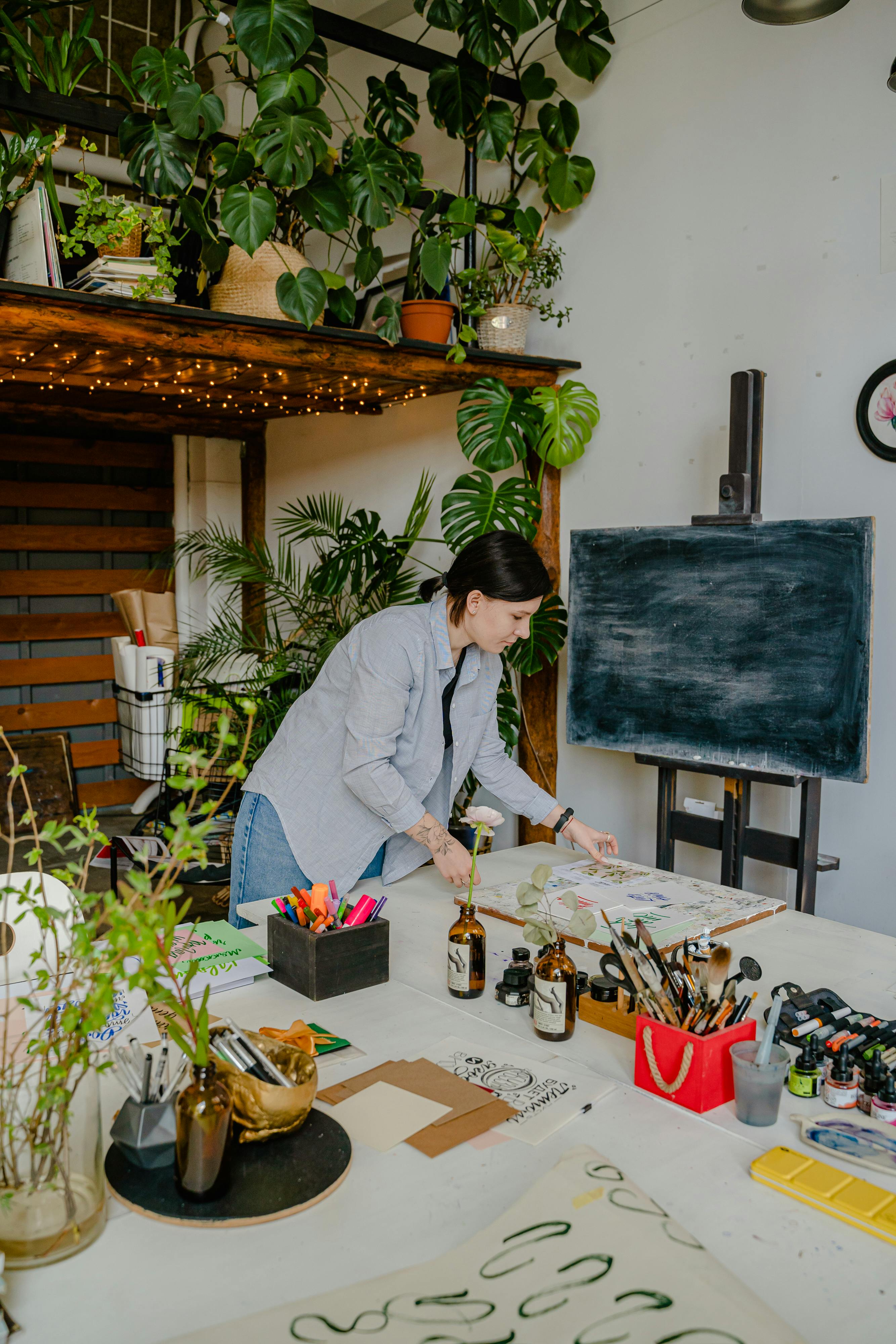 Artist working in a vibrant indoor workspace with plants and art supplies.