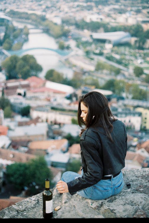 Free Serious woman sitting on stone parapet Stock Photo