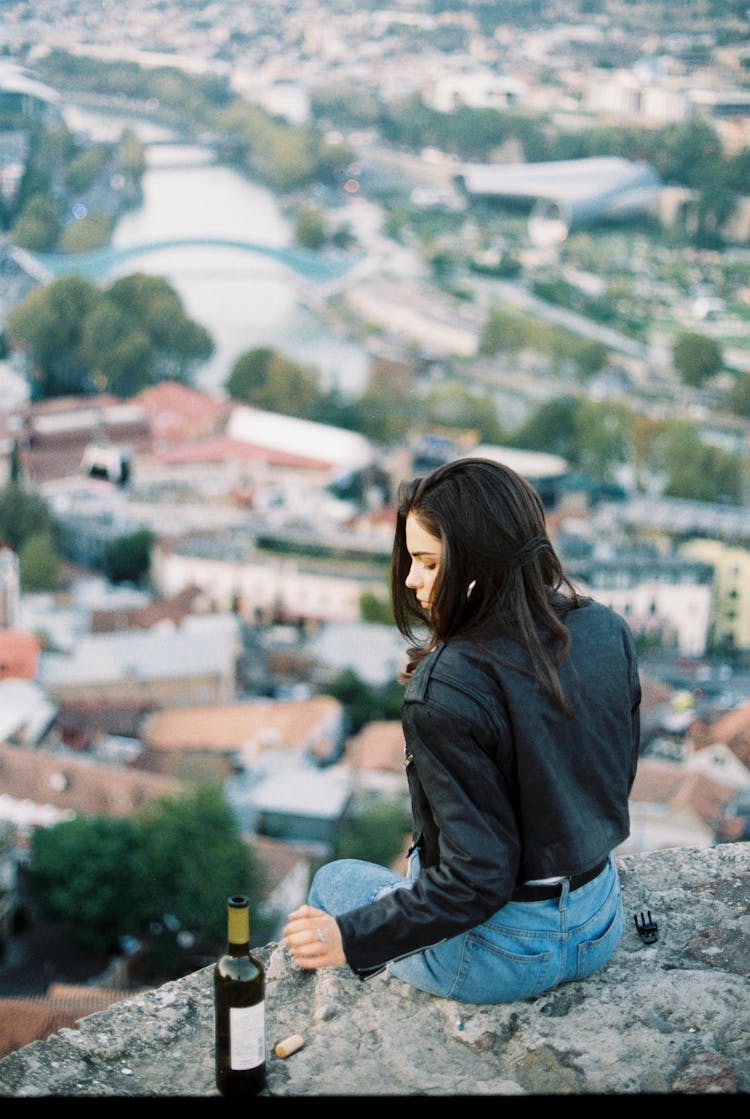 Serious Woman Sitting On Stone Parapet