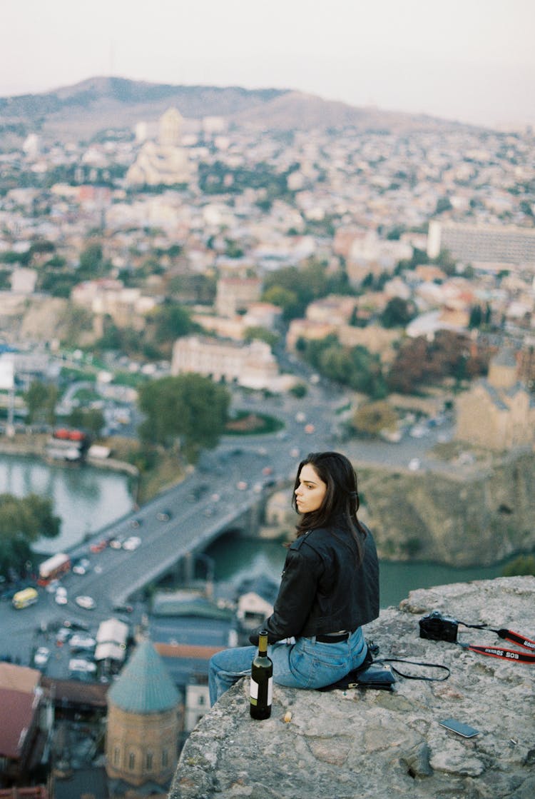 Young Woman Enjoying View Of City On Stone Parapet