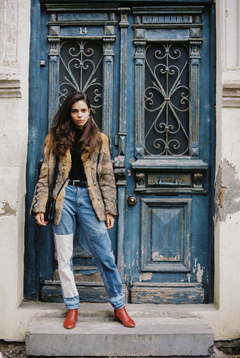 Woman in fur coat and denim at a rustic doorway