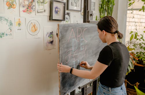 Woman in Black Shirt Writing on the Blackboard