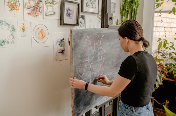 Woman In Black Shirt Writing On The Blackboard