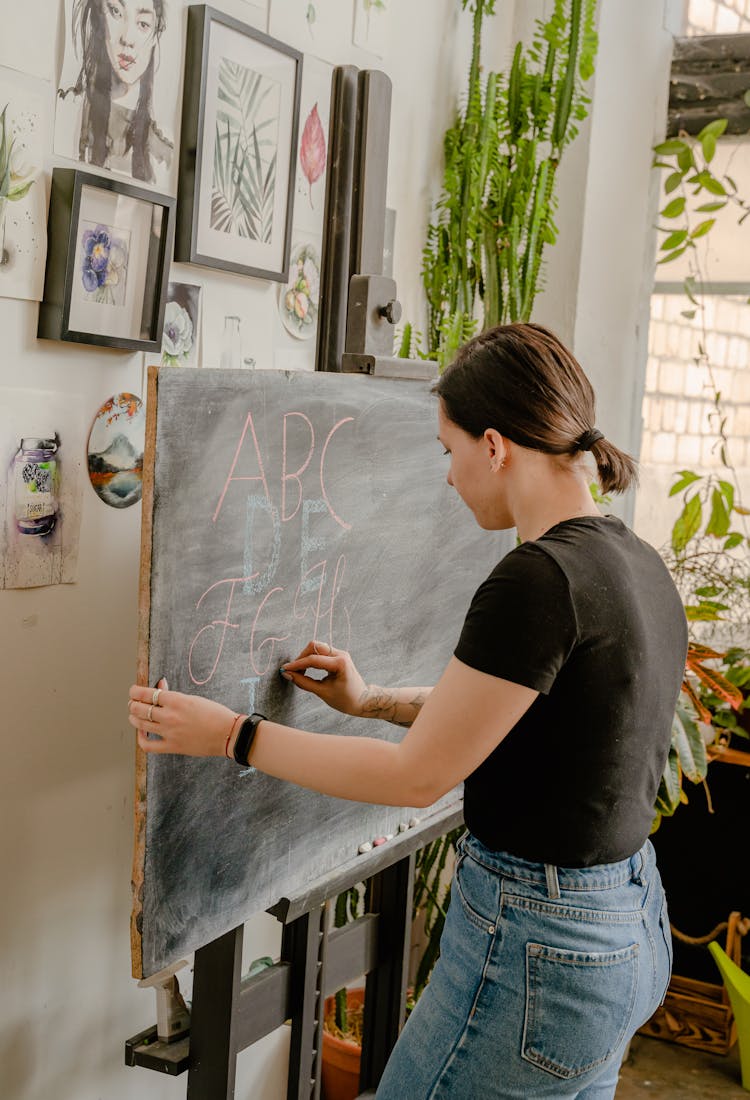 Woman In Black Shirt  Writing On The Chalkboard