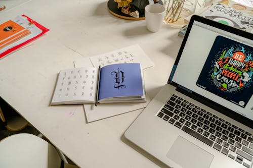 Laptop on White Table Near the Calligraphy Book