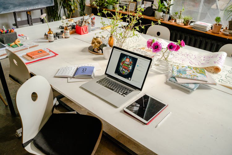 A Laptop, Tablet And Art Supplies On A Table 