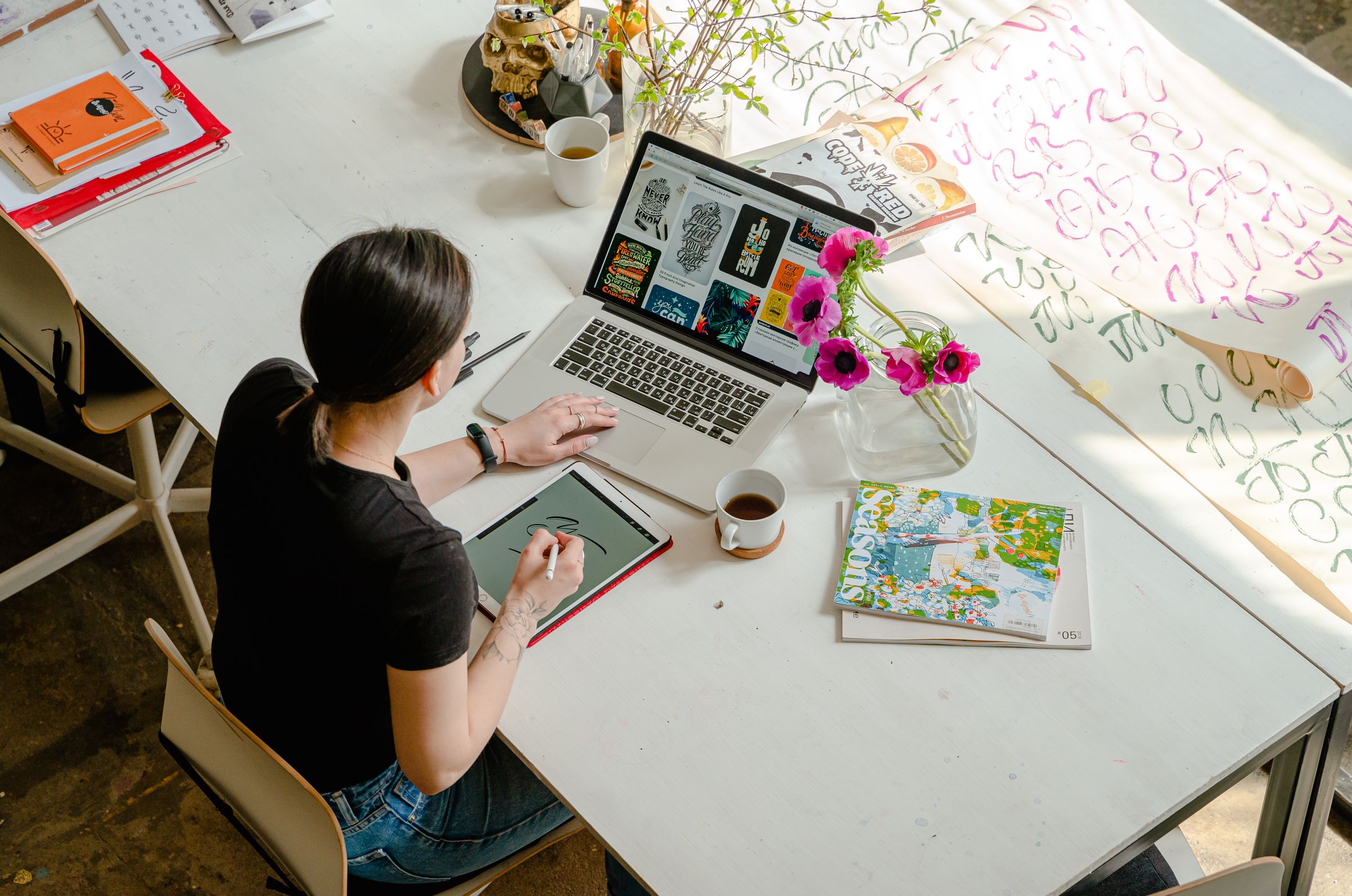Woman working at a creative desk with a laptop and tablet