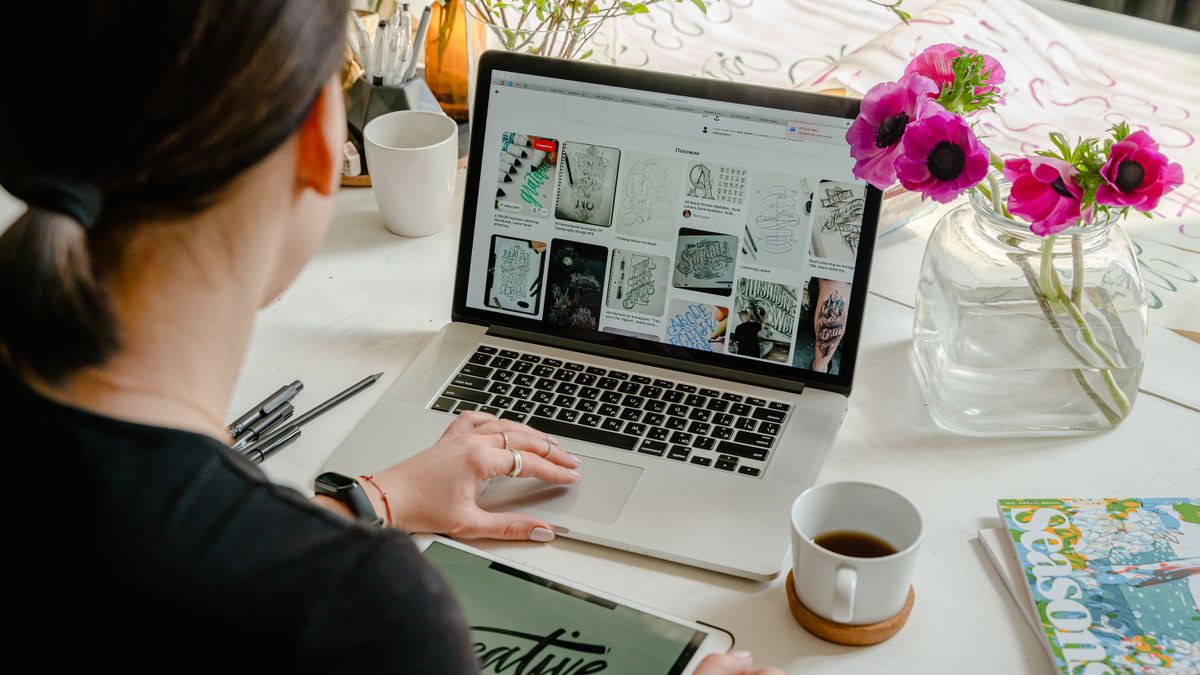 Woman focused at a creative workspace with a laptop and tablet, illustrating the quiet, concentrated effort that drives early-stage side projects