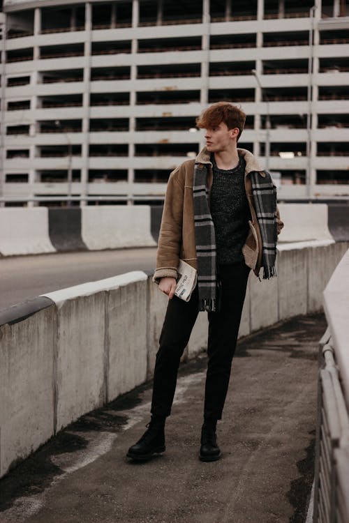 Man in Brown Jacket and Black Pants Holding a Daily News