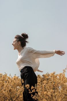 一位快乐的女子在户外张开双臂，身旁点缀着黄色花朵，画面捕捉了她的自由与表情