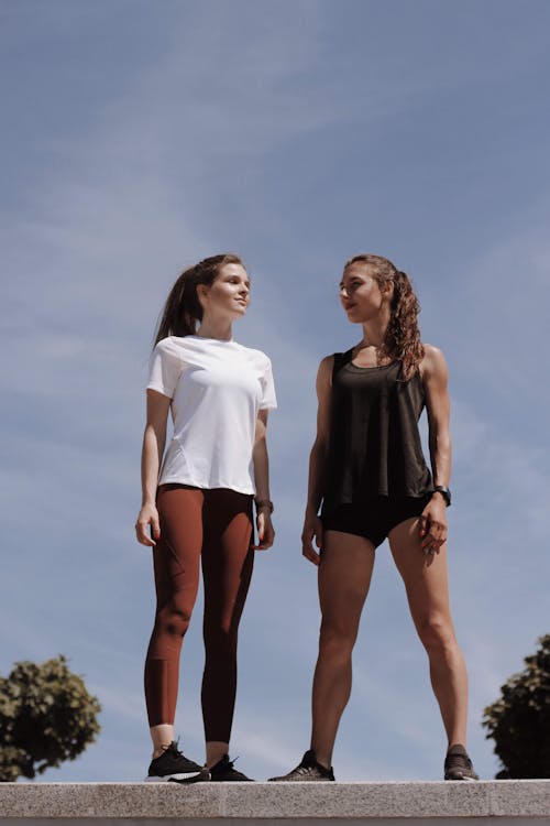 Women in Active Wear Standing Under the Blue Sky and White Clouds