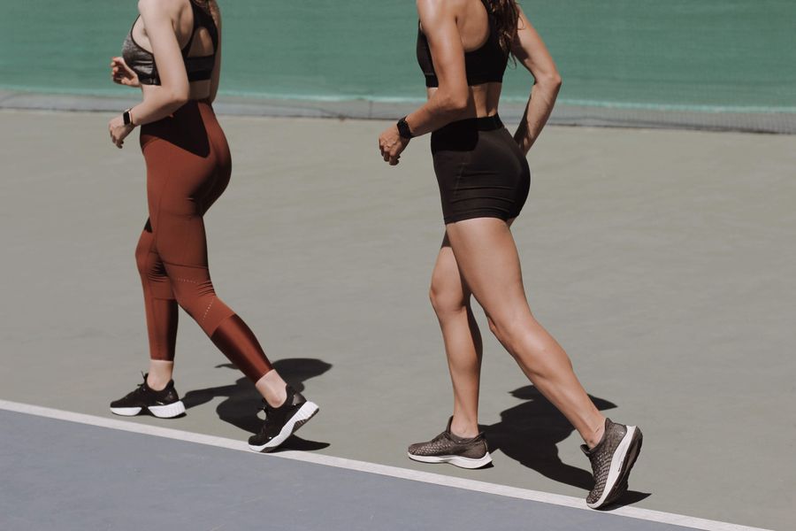 Two women stretching together on an outdoor track