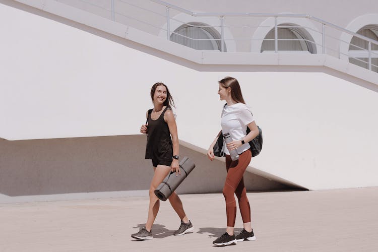 Women Walking Together Carrying Yoga Mat And Black Shoulder Bag