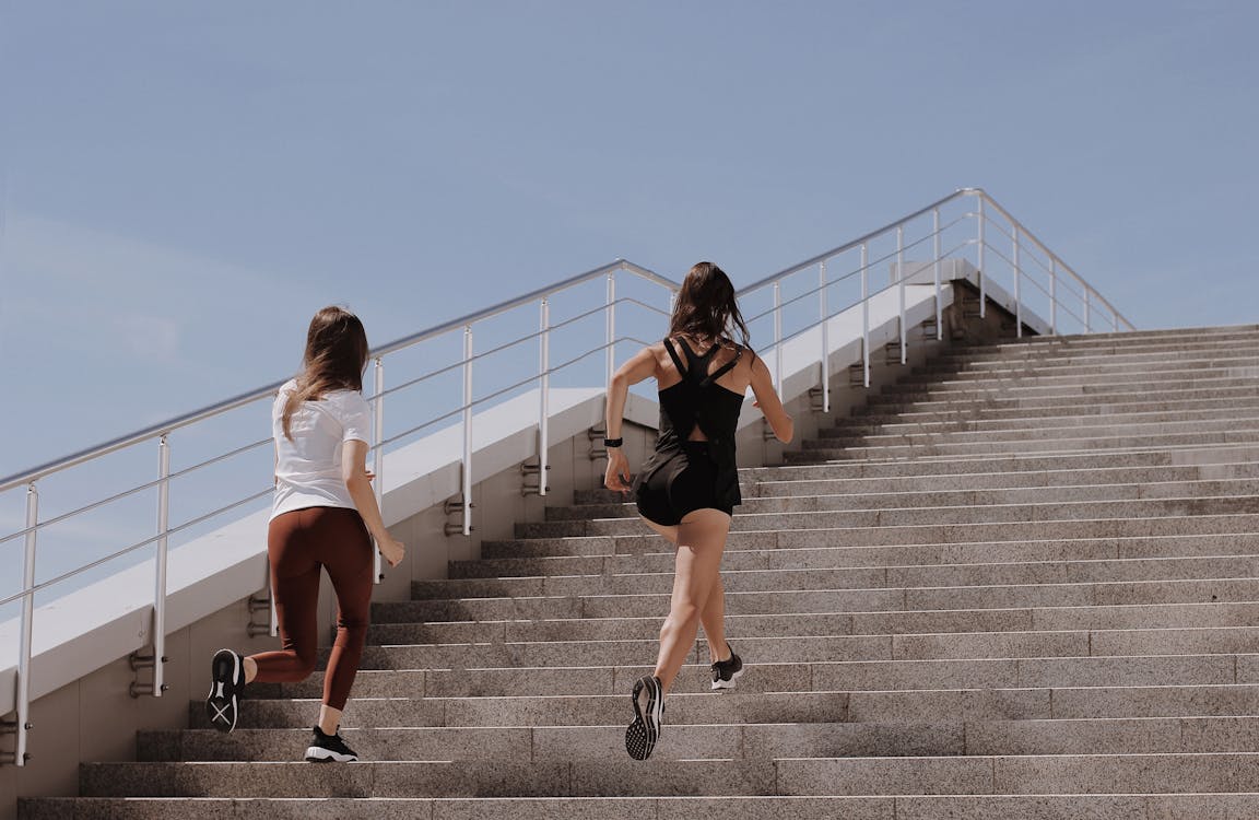 Free Two women running up stairs outdoors, embodying fitness and wellness. Stock Photo