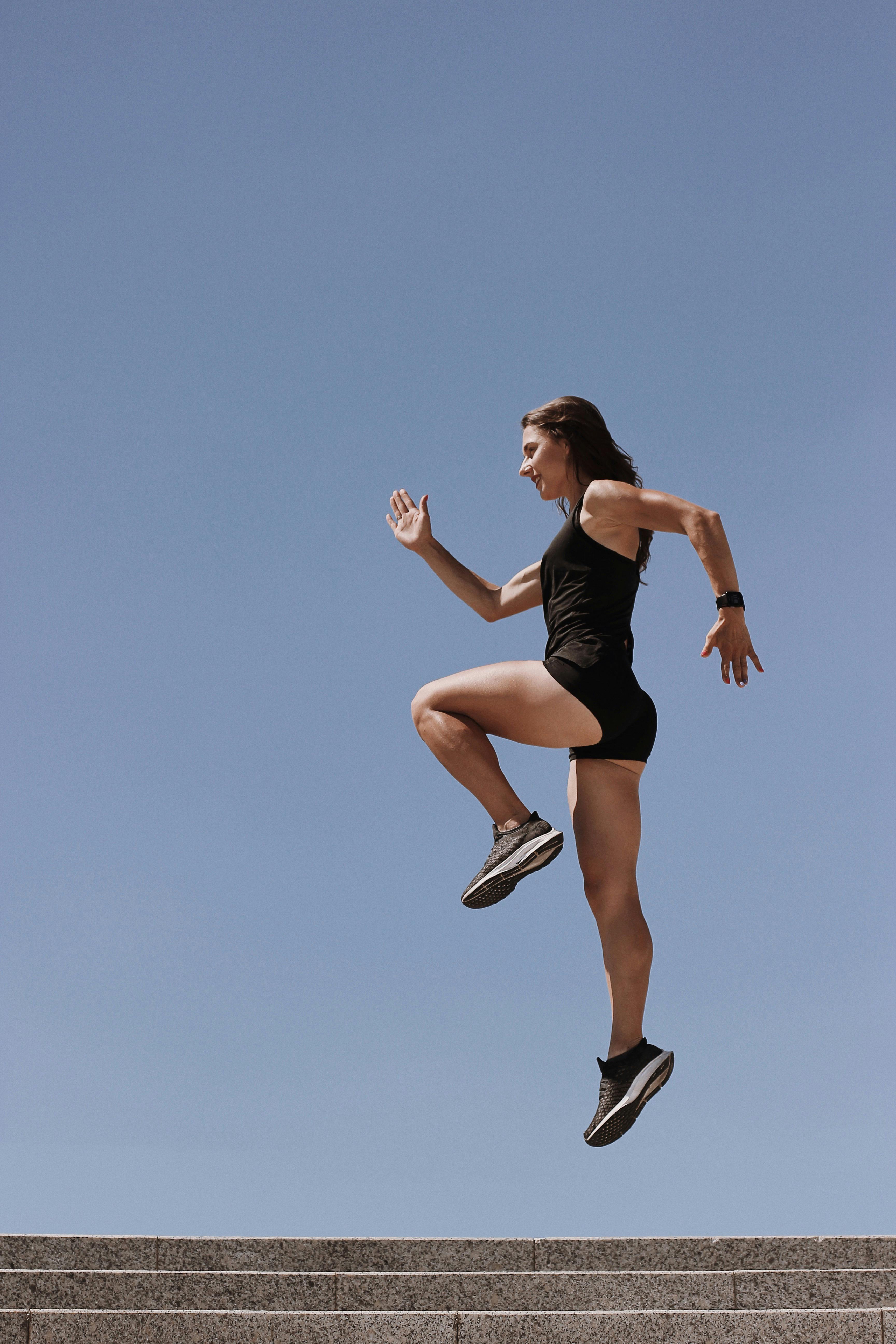 woman in black tank top and white shorts jumping