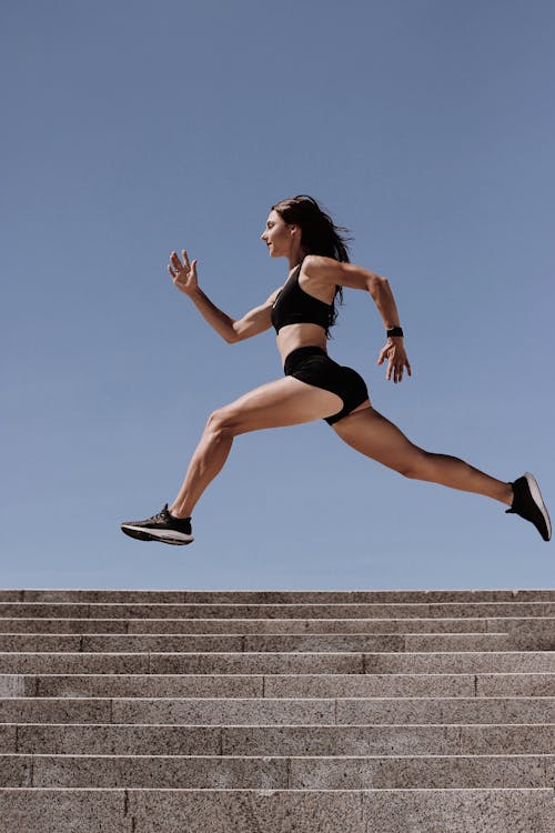 Woman in Athletic Wear Running Near the Concrete Stairs