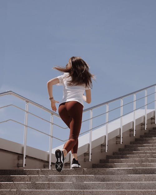 Woman in White Shirt and Leggings Running on the Concrete Stairs