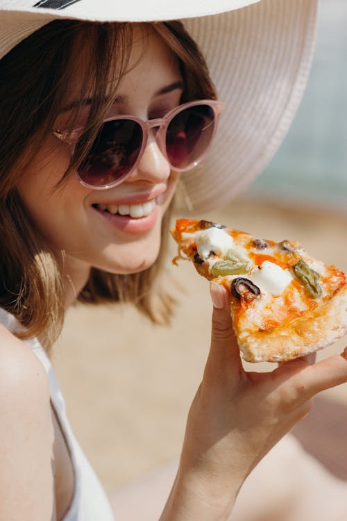 Woman Wearing a Summer Hat Holding Sliced Pizza