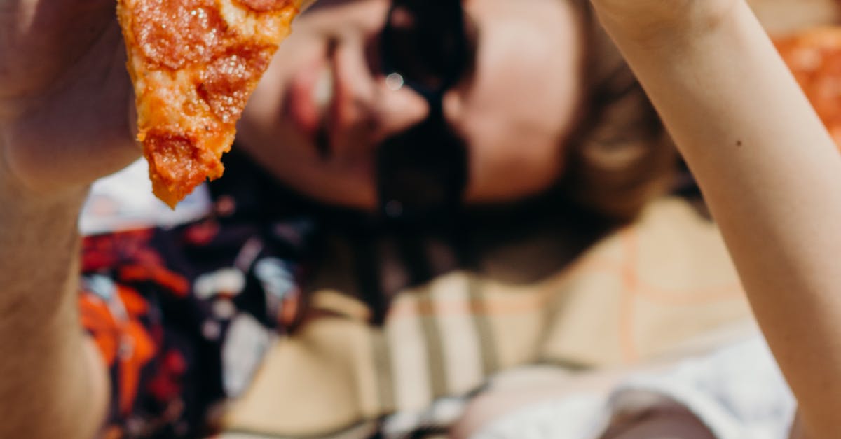 Two friends enjoying a sunny picnic with pepperoni pizza slices. Perfect summer outing.