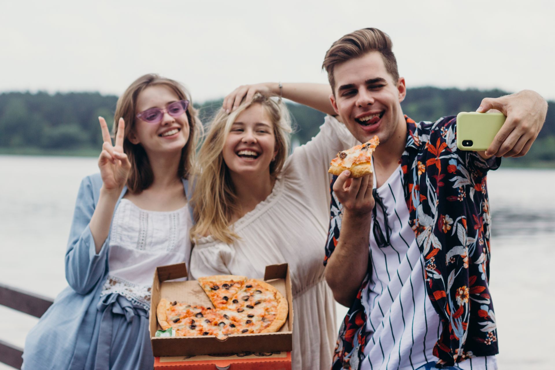 A Group of Friends Taking Selfie while Holding a Pizza