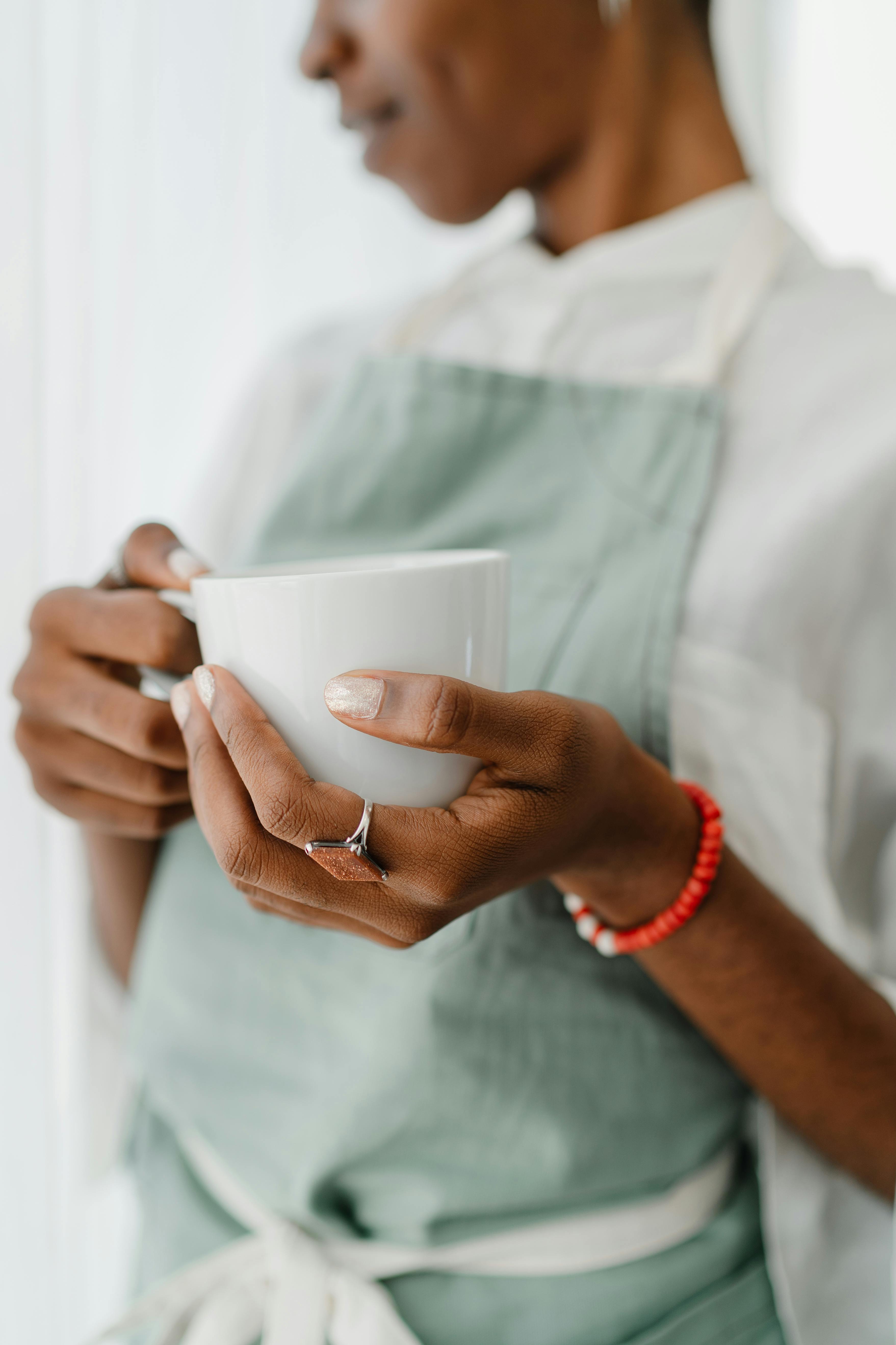 crop black female barista with coffee mug in coffee shop