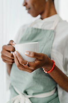 咖啡师系着围裙，端着咖啡杯，营造出温暖、迷人的氛围
