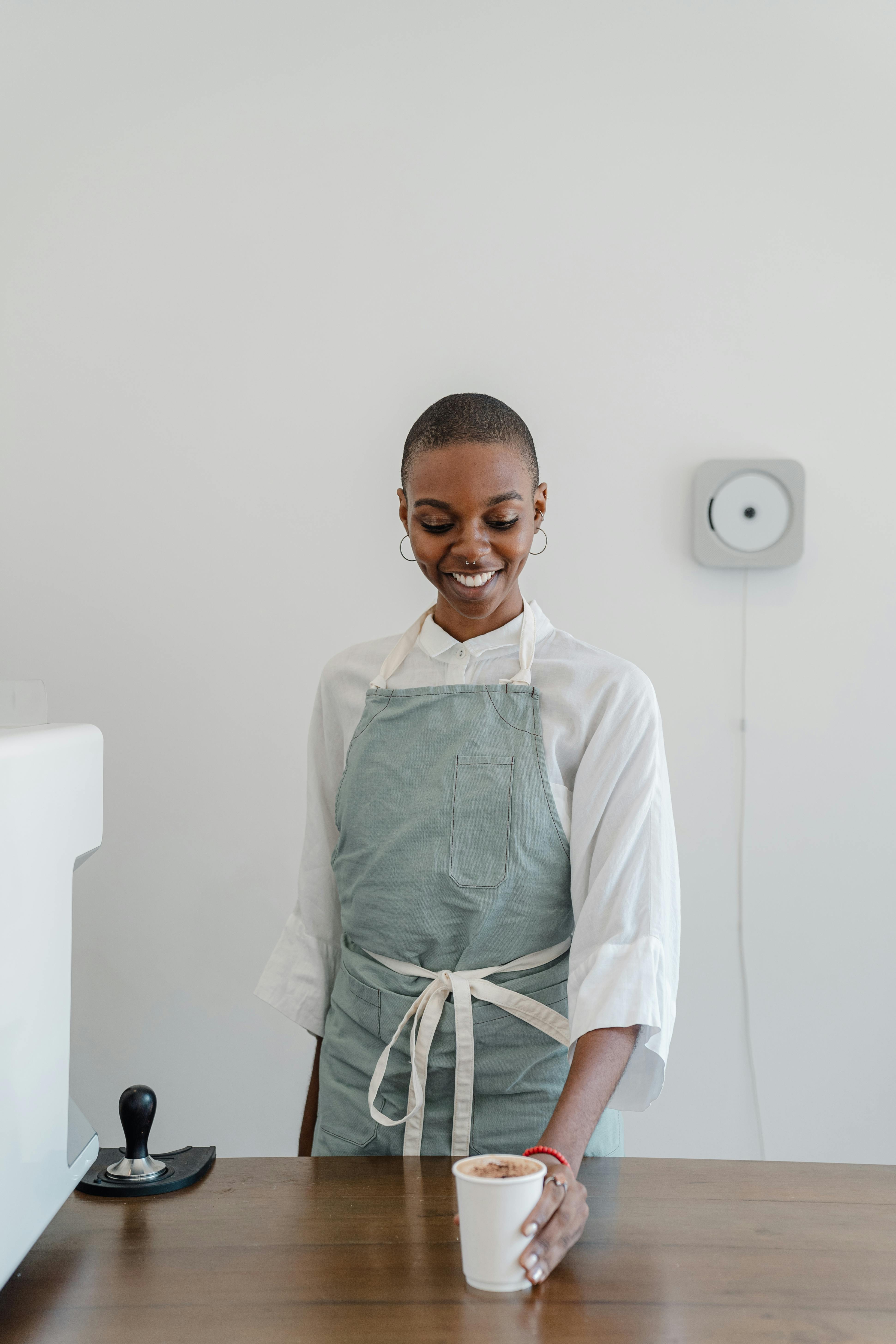 smiling african american female barista offering coffee in paper cup