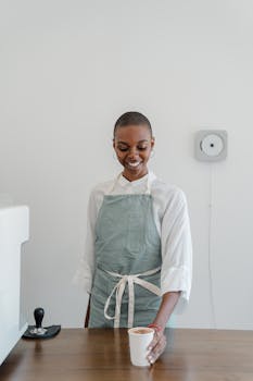Cheerful barista offering a freshly made cappuccino at a modern café.