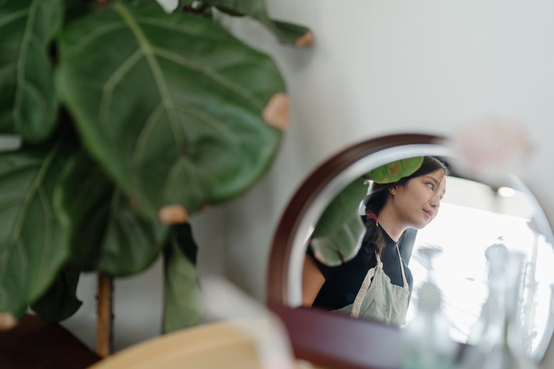 Mirror reflection of young Asian woman in apron